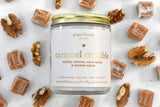 Caramel crumble candle in a jar with caramel candies and walnuts scattered around.