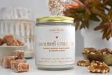 Caramel crumble candle in a jar surrounded by caramel candies and walnuts. 